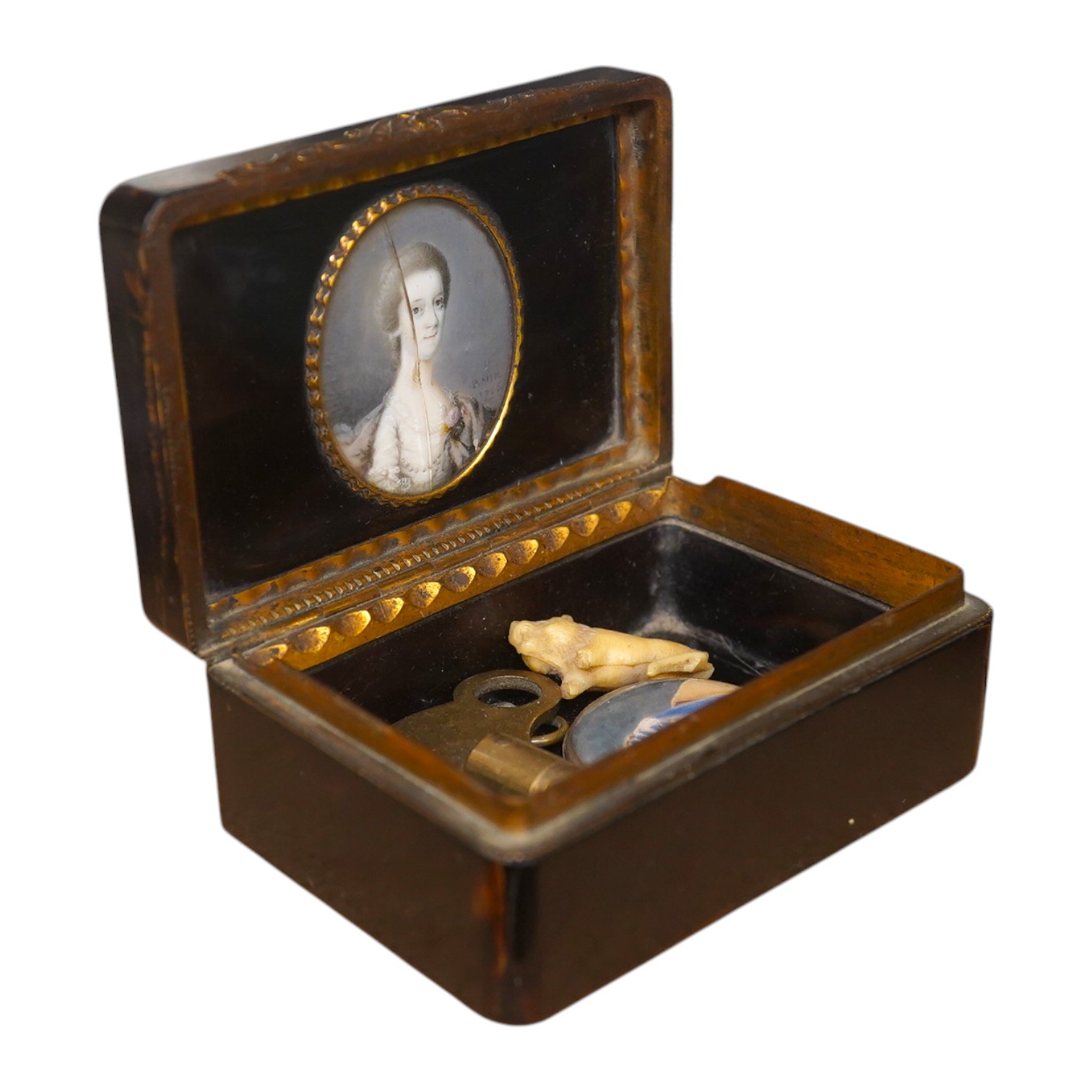 A George III tortoiseshell and gilt metal inlaid ivory portrait miniature snuff box and another portrait miniature pendant with a lock of hair, snuff box 8cm x 15cm. Condition - small chip to base and glass to miniature